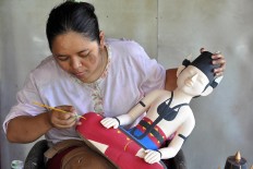  Tukiran’s daughter-in-law carefully paints the sculpture of the groom. JP/Magnus Hendratmo