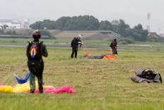 Three parachuters fold their parachutes after landing at the Air Force base. JP/Arya Dipa