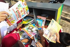Start young: Students enthusiastically browse through a collection of books from Wahyudin's mobile library. JP/Bangkit Jaya Putra