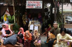 Some visitors of the 2017 festival sit in front of a food stall selling snacks. JP/Aman Rochman