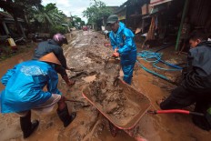 Villagers work together to clean up thick mud covering the road connecting Imogiri and Siluk villages in Bantul regency. JP/Aditya Sagita