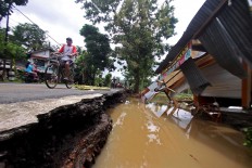Villagers pass by a house destroyed by floods in Dogongan village, Imogiri district, in Bantul regency, Yogyakarta, on Wednesday Nov. 29, 2017. JP/Aditya Sagita