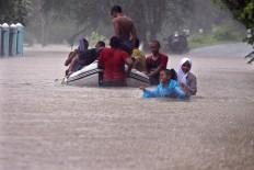 Villagers use a rubber dinghy to pass through chest high flood waters, in Gunungkidul regency. Heavy rains inundated the area in up to two meters of water. JP/Aditya Sagita
