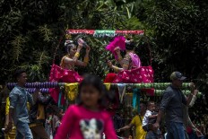 Girls – who have been dressed up – are being carried from their houses to the nearest field for the Henauka Wowine coming of age celebration. Antara/Rosa Panggabean