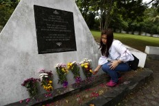 An Acehnese places a flower bouquet at the mass burial site during the commemoration of the tsunami in Banda Aceh, Dec. 26, 2017. JP/Hotli Simanjuntak
