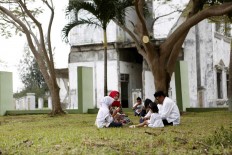 A family prays at the burial site during the tsunami commemoration. JP/Hotli Simanjuntak