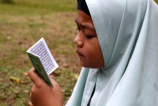 A young girl reads the Yassin verse while praying at the burial site. JP/Hotli Simanjuntak