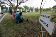 A man leads his family to pray at the burial site. JP/Hotli Simanjuntak