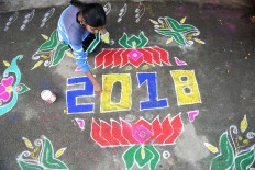 A woman applies coloured powder to a "rangoli", a Hindu ritual design, to usher in the New Year in front of a home in Hyderabad on January 1, 2018. 
Rangolis are drawn in front of homes early in the morning to welcome relatives and friends to mark the New Year.  AFP/Noah Seelam