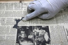 Missing piece: An employee shows a damaged newspaper. JP/Maksum Nur Fauzan.