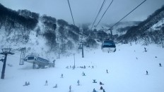 Goryu-Toomi cable cars travel above visitors skiing on Toomi slope. The area, suitable for beginners and families, opens at 6:30 a.m. and operates until 9:30 p.m. JP/Agnes Anya