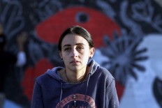 Suha Sultan, a 20-year-old graffiti artist and student, looks on as she sits in front of a mural on a wall in the Jordanian capital Amman on December 16, 2017.
A tiny group of graffiti artists are on a mission -- daubing flowers, faces and patterns across the capital Amman to bring more colour to the lives of its four million inhabitants.
In a conservative society like Jordan's, the graffiti artists have constantly had to challenge convention to carve out a niche for their works, though still with limits as they steer away from politics and religion. AFP/Khalil Mazraawi 