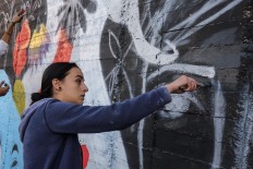 Suha Sultan, a 20-year-old graffiti artist and student, uses a brush to draw a mural on a wall in the Jordanian capital Amman on December 16, 2017.
A tiny group of graffiti artists are on a mission -- daubing flowers, faces and patterns across the capital Amman to bring more colour to the lives of its four million inhabitants.
In a conservative society like Jordan's, the graffiti artists have constantly had to challenge convention to carve out a niche for their works, though still with limits as they steer away from politics and religion. AFP/Khalil Mazraawi 