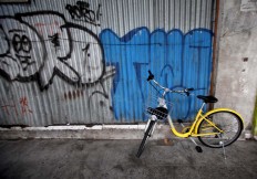 A yellow bicycle is seen parked on an empty sidewalk. JP/Boy T. Harjanto