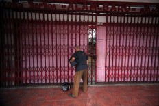A shop attendant closes a store gate in the afternoon. JP/Boy T. Harjanto