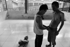 A nurse helps a patient put on his pants while another lies on the floor. Antara/Hafidz Mubarak