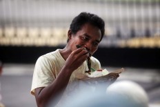 A man bites into his fried catfish. JP/ Boy T. Harjanto