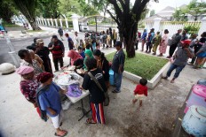 Poor people wait in line at the food stall, which opens at 12 p.m. JP/ Boy T. Harjanto