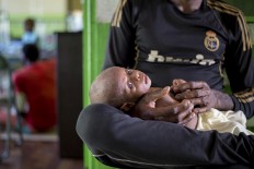 A Papuan man holds his child at a local hospital handling measles and malnutrition patients in Agats, the capital of Asmat district in Indonesia's easternmost Papua province, on January 25, 2018. Some 800 children have been sickened by a measles-and-malnutrition outbreak in Indonesia's remote Papua province, officials said January 25, with as many as 100 people, mostly toddlers, feared to have been killed in the outbreak. AFP/ Bay Ismoyo