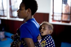 A Papuan mother carries her sleeping child on her back at a temporary hospital handling measles and malnutrition patients in Agats, the capital of Asmat district in Indonesia's easternmost Papua province, on January 25, 2018. Some 800 children have been sickened by a measles-and-malnutrition outbreak in Indonesia's remote Papua province, officials said January 25, with as many as 100 people, mostly toddlers, feared to have been killed in the outbreak. AFP/ Bay Ismoyo