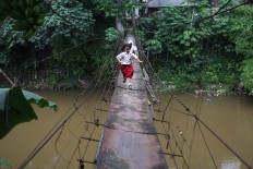 Schoolchildren run across a bridge in Srengseng Sawah, South Jakarta on Tuesday, January. 23. The bridge, which is in poor condition, serves as a main access point for residents in the area. JP/Seto Wardhana.
