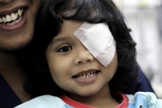 All smiles: Falisha Ilyarsi smiles as she poses for a photo with her father, Rizwan Ilyasin. The two-year-old lost her right eye when she was two months old and her left one early this year. JP/ Ben Latuihamallo