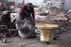 A worker moves a 170 kg bronze bell to be polished. The price of the bell is Rp 65 million. JP/Magnus Hendratmo