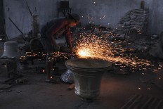 Sparks fly when a worker polishes the bell. He faces the wall so he can collect the leftover material. JP/Magnus Hendratmo
