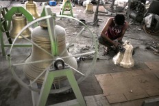 A worker uses a grinder to smooth the surface of the bronze bell. JP/Magnus Hendratmo