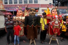 No clash of culture: A father and child pose in front of Chinese and Javanese puppet characters. JP/ Maksum Nur Fauzan