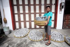 A worker, Gunanto, carries cooking tools. JP/Boy T. Harjanto