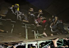 Actors are reflected in a puddle while they take a break backstage. JP/Aditya Sagita