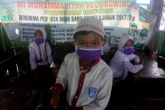 A boy’s smile is hidden behind his surgical mask. JP/Maksum Nur Fauzan