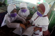 Three female students wear surgical masks while studying. JP/Maksum Nur Fauzan