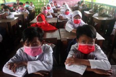 Muhammadiyah elementary school students wear surgical masks in class due to the strong smell from a nearby factory’s chemical waste. JP/Maksum Nur Fauzan