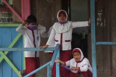 Two girls take off their surgical masks during a school break. JP/Maksum Nur Fauzan