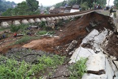 Residents watch as police and military personnel search for missing people after the concrete support structure of a railway track collapsed in Warung Menteng village, Cijeruk district, Bogor regency, West Java, on Tuesday, February 6. The incident, which was caused by a landslide on Monday, killed five people and destroyed three houses. JP/PJ Leo