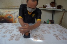 A worker prints batik with an ondel-ondel motif. JP/Endro Prakoso