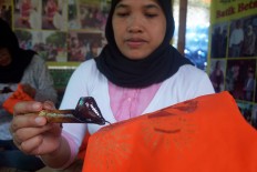 A woman draws a batik motif using the canting (copper pen filled with heated wax). JP/Endro Prakoso