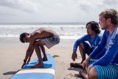 Wave riders: A foreign surfer and two locals prepare to hit the waves at Kuta Beach in Badung, Bali. JP/ Anggara Mahendra