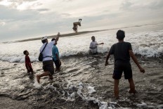 Into the waves: A man throws a duck into the ocean as an offering during Melasti. JP/Agung Parameswara