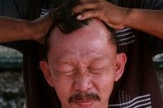 Pain is etched on the face of a patient undergoing cupping therapy. JP/Boy T. Harjanto