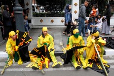 Exhausted performers from Lamandau regency, Central Kalimantan, take a rest on the sidewalk. JP/Arya Dipa