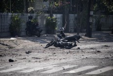 A damaged motorbike is seen at the scene outside a church following a suicide bomb in Surabaya on May 13, 2018. At least two people were killed and 13 others injured in bomb attacks, including a suicide blast, targeting churches in Indonesia's second biggest city Surabaya, police said. AFP/ Juni Kriswanto