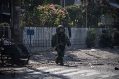 An Indonesian bomb squad member examines the site following a suicide bomb outside a church in Surabaya on May 13, 2018. At least two people were killed and 13 others injured in bomb attacks, including a suicide blast, targeting churches in Indonesia's second biggest city Surabaya, police said. AFP/ Juni Kriswanto