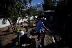 A man scatters rose petals on top of his relative’s grave. JP/Boy T. Harjanto