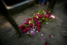 Red roses are placed on top of a tomb. JP/Boy T. Harjanto