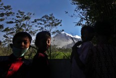 Three children play at the cemetery with Mount Merapi visible in the background. JP/Boy T. Harjanto