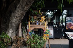 A spirit house is placed under a tree in front of a restaurant in Chiang Mai, Thailand. JP/Anggara Mahendra