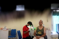 Still and steady: A man sits solemnly during the removal of his tattoo. JP/Maksum Nur Fauzan